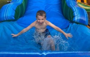 Kid splashing in pool of inflatable water slide